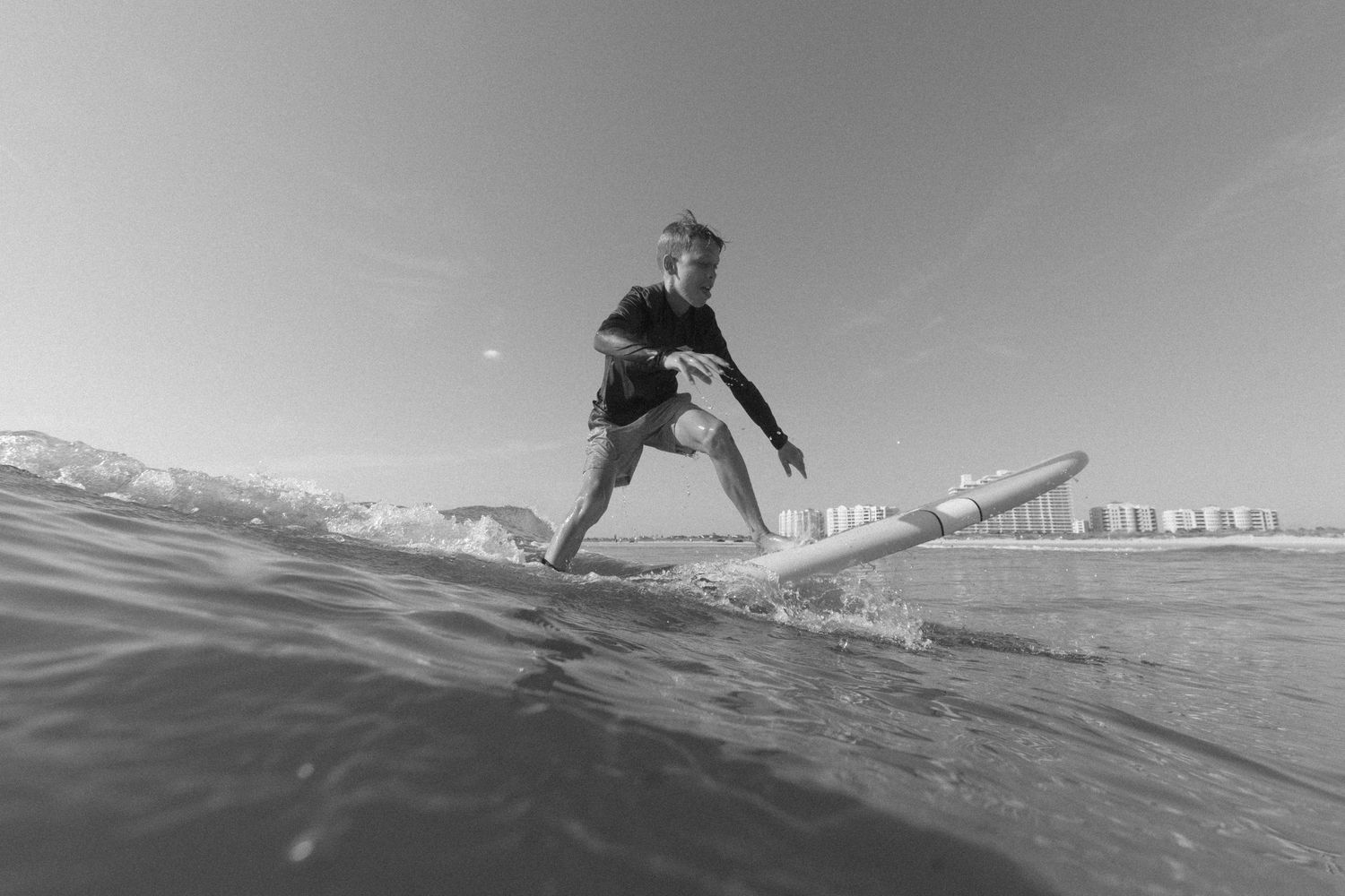 A surfer rides a wave while performing aerial maneuvers in black and white photography.