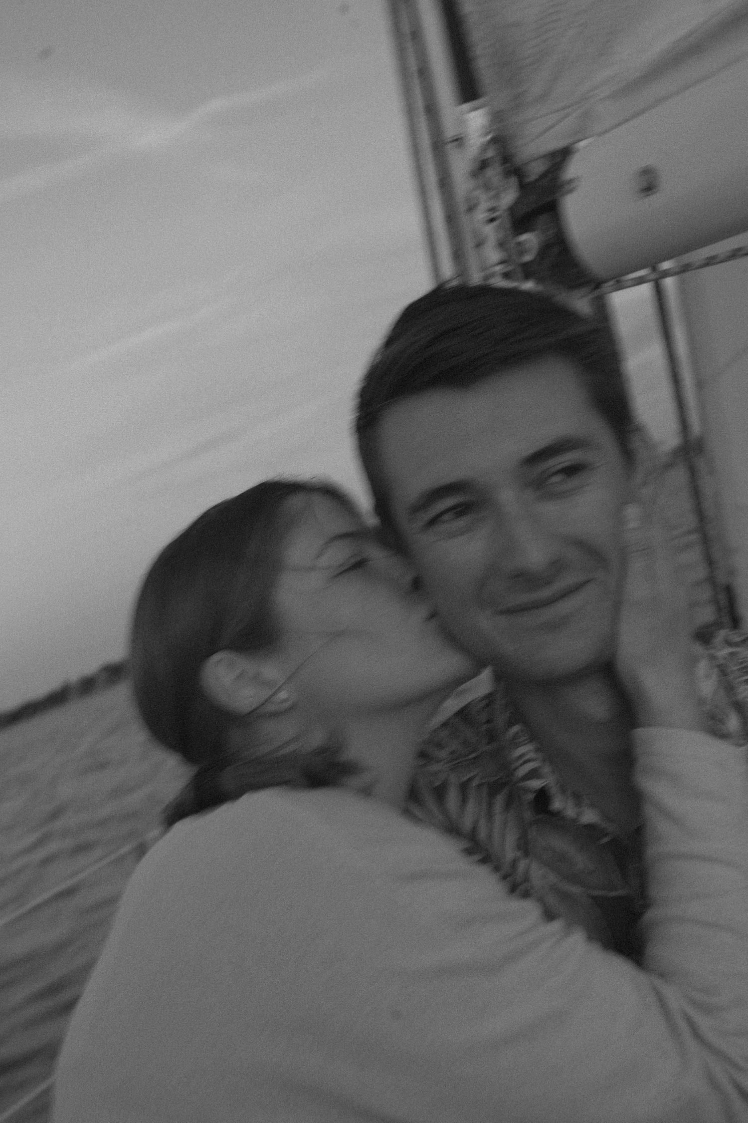 A black and white romantic portrait of a couple in a tender moment together, captured in soft lighting.