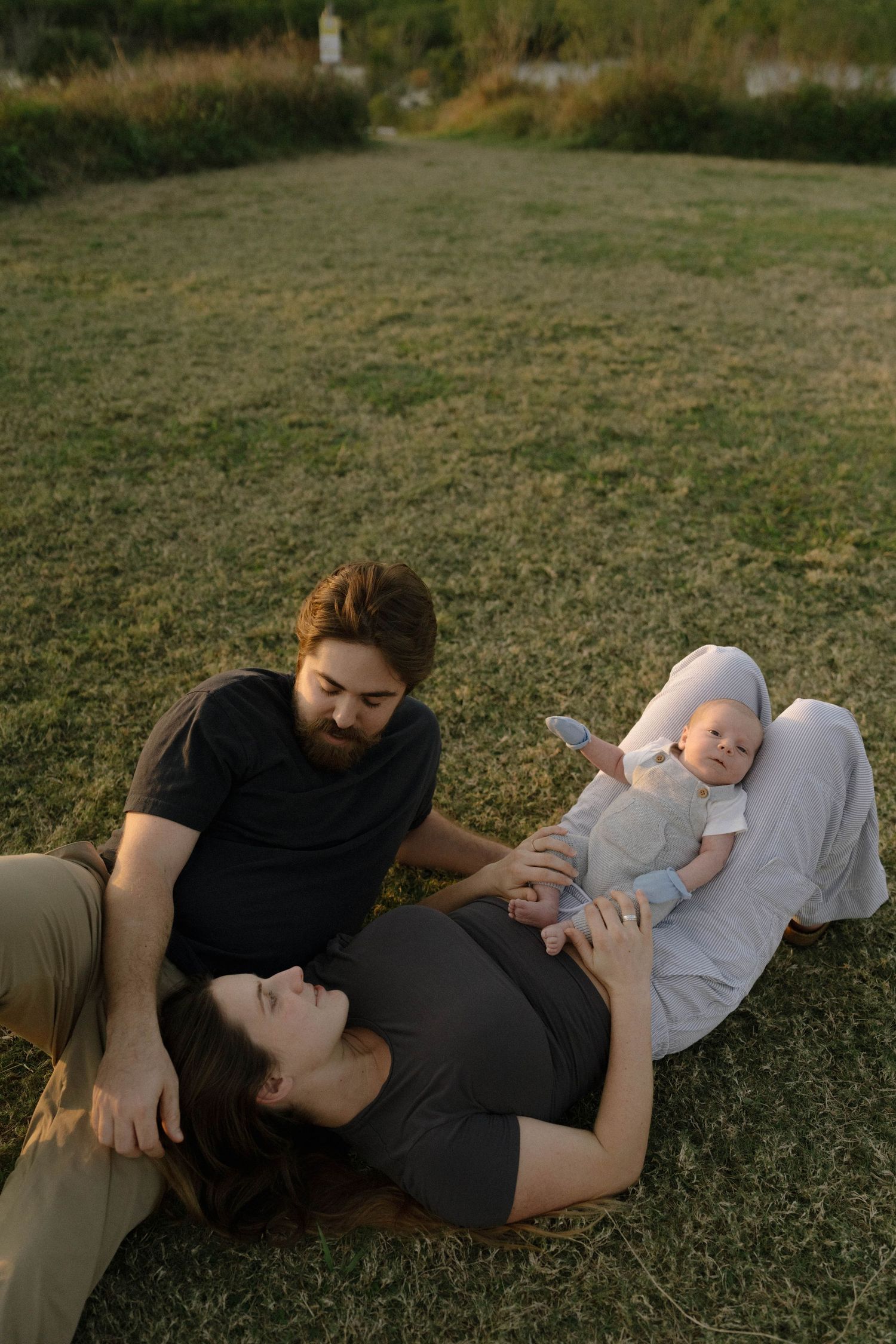 A couple relaxes together on a grassy lawn during a peaceful afternoon outdoors.