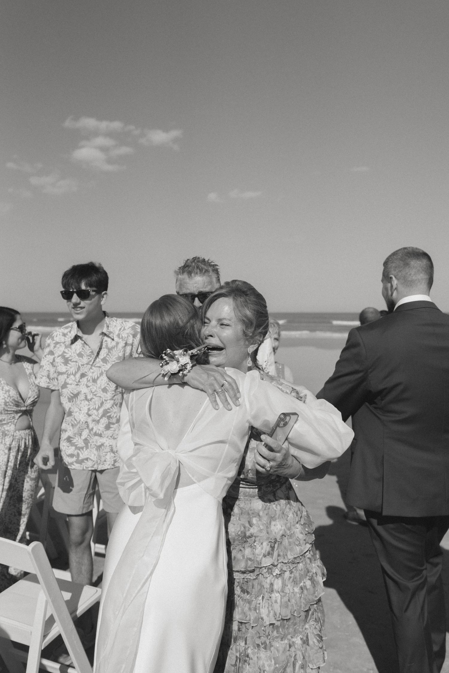 A sequence of black and white photographs showing people embracing and celebrating on a beach.