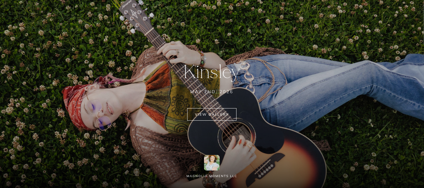 Portrait photographer Kinsley website homepage featuring a woman lying in grass with a guitar.