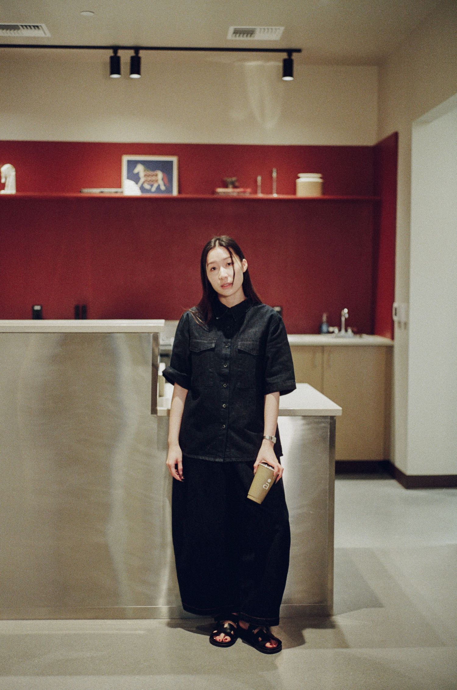 A series of photos showing a person in black clothing posing in a room with red walls and track lighting.
