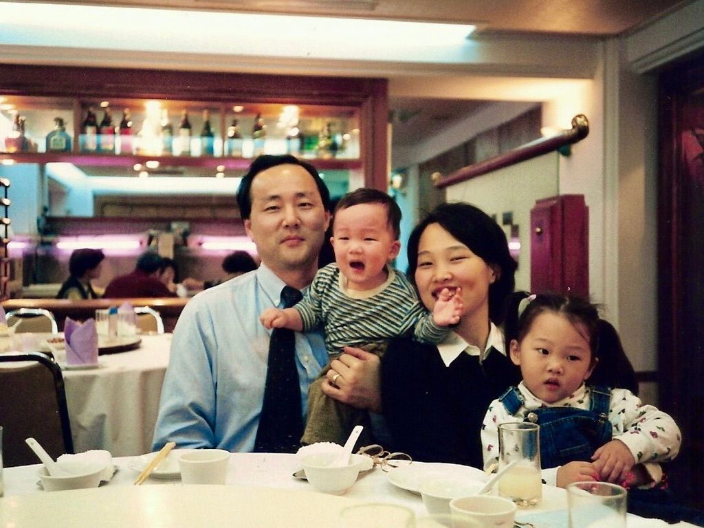 A group of people laugh and smile together while dining at a restaurant table.