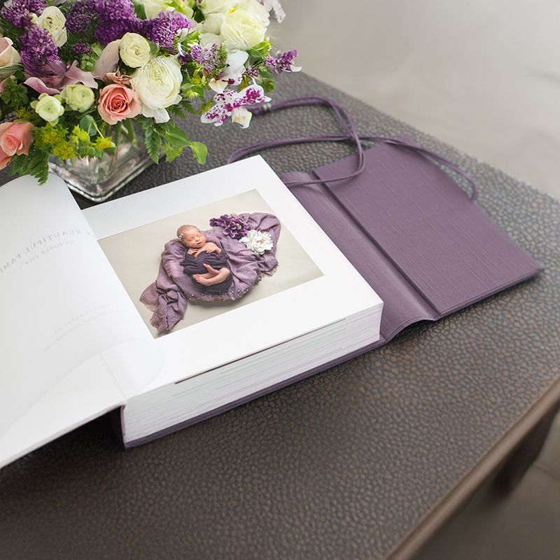 Elegant floral arrangement with purple and white flowers sits atop a luxurious stationery set in varying shades of plum.