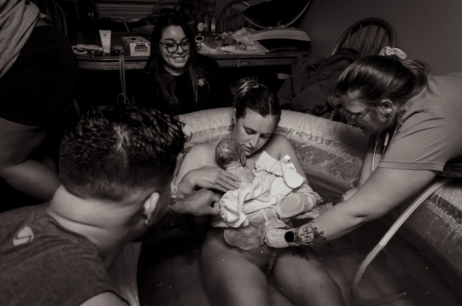 Black and white photograph of a newborn's first moments surrounded by medical support.