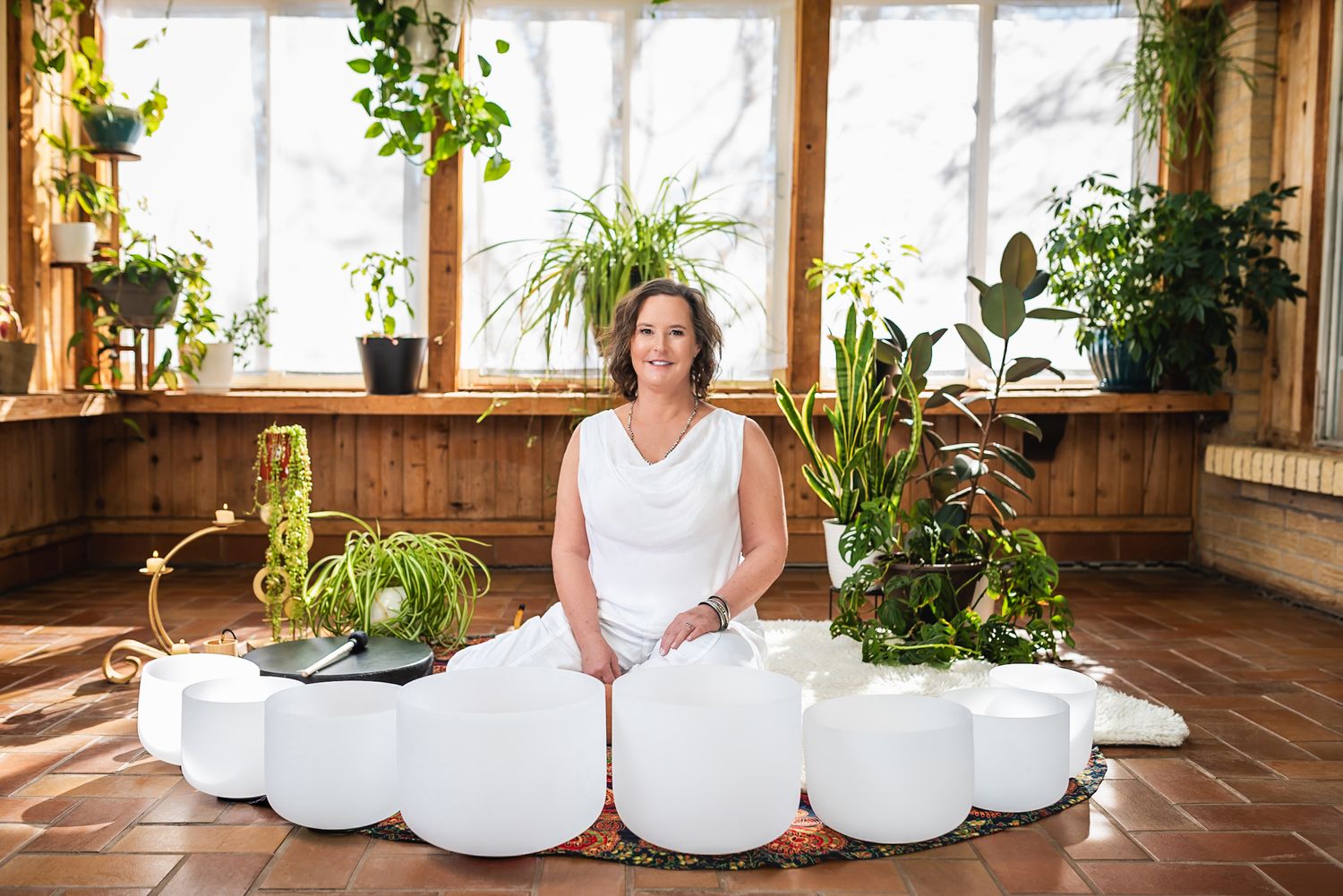 A series of white ceramic planters arranged in a row along a rustic wooden floor with green plants.