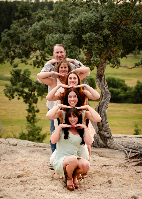 A fun outdoor photo series showing playful poses with three people making heart shapes against a natural backdrop.