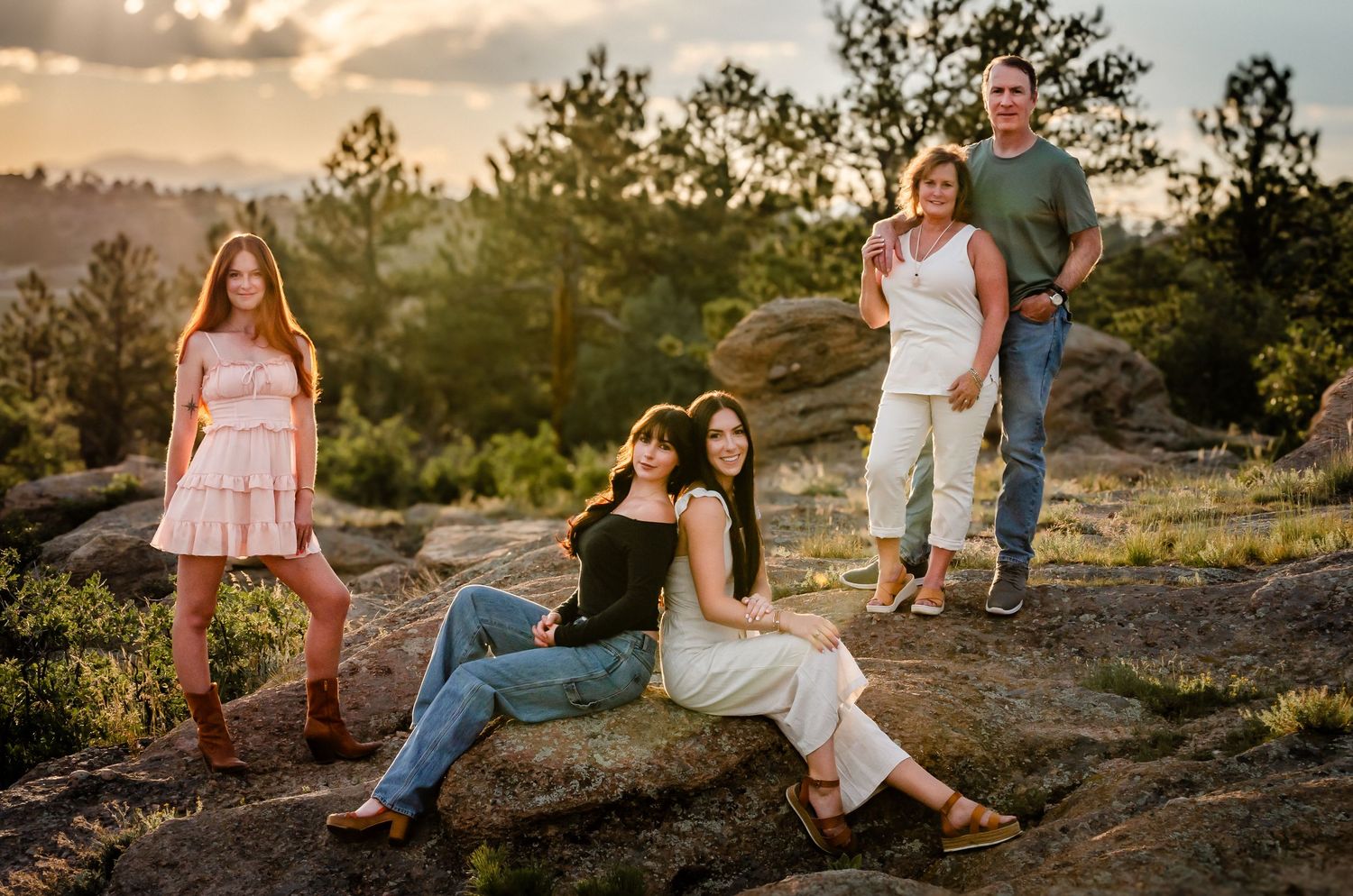 Family portrait at sunset with rocky mountain backdrop and pine trees.