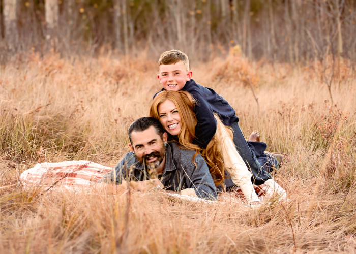 A series of engagement photos showing a couple laying in tall golden grass during an autumn photoshoot.