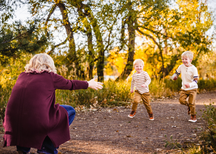 Children playing and running on a dirt path during golden hour in autumn with trees in background.
