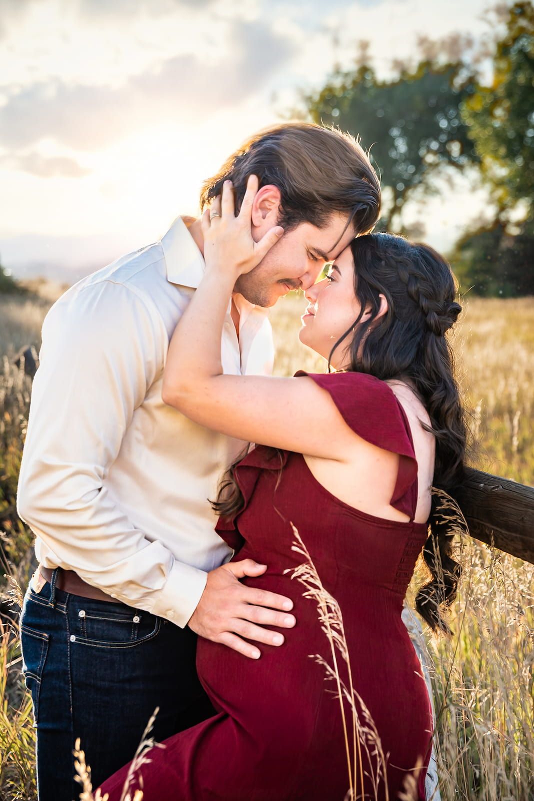A romantic couple embraces in a golden wheat field during sunset, creating a series of intimate poses.