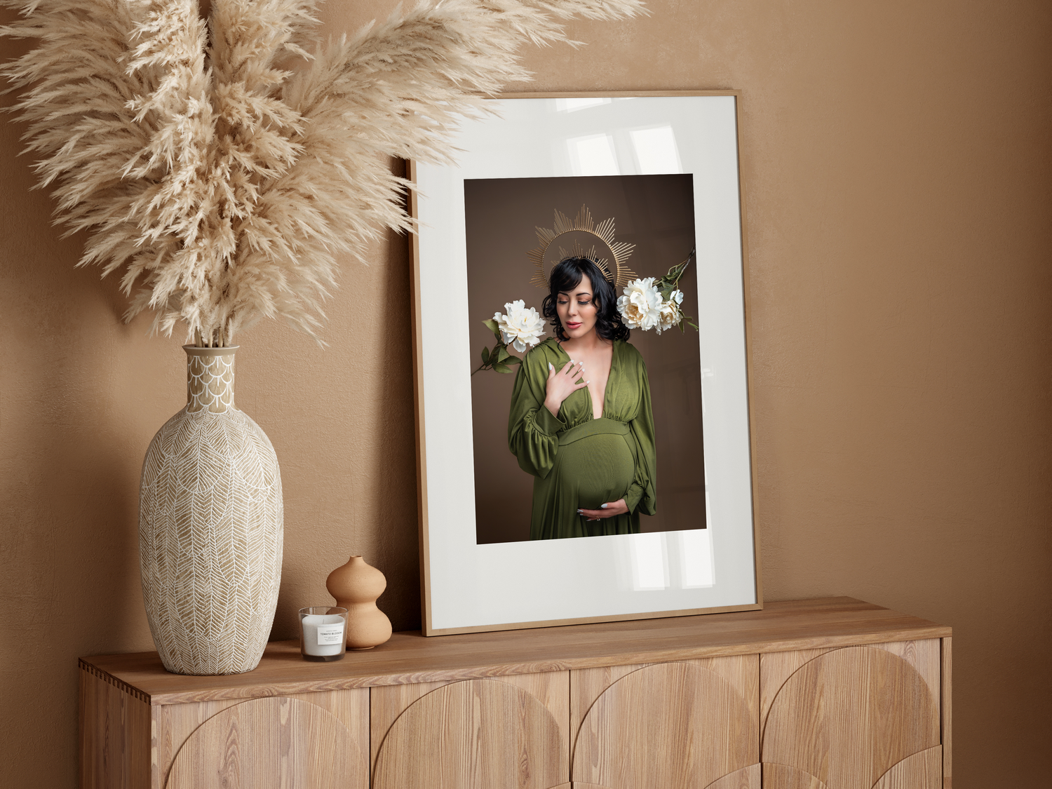 Neutral beige toned interior design vignette with dried pampas grass in vase and framed artwork on wooden console table.