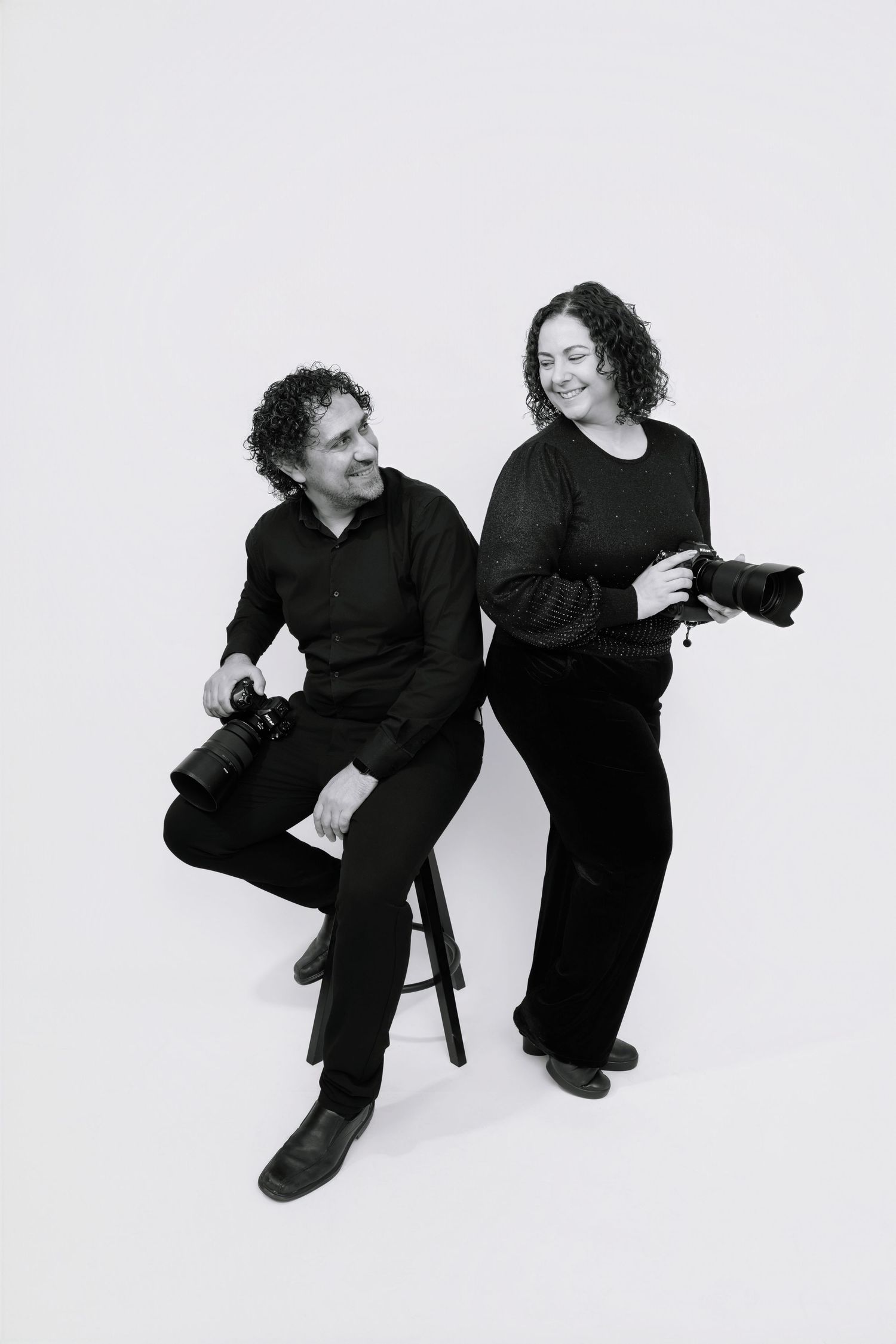 Two performers in black attire dance expressively against a white background in a sequence of dynamic movements.