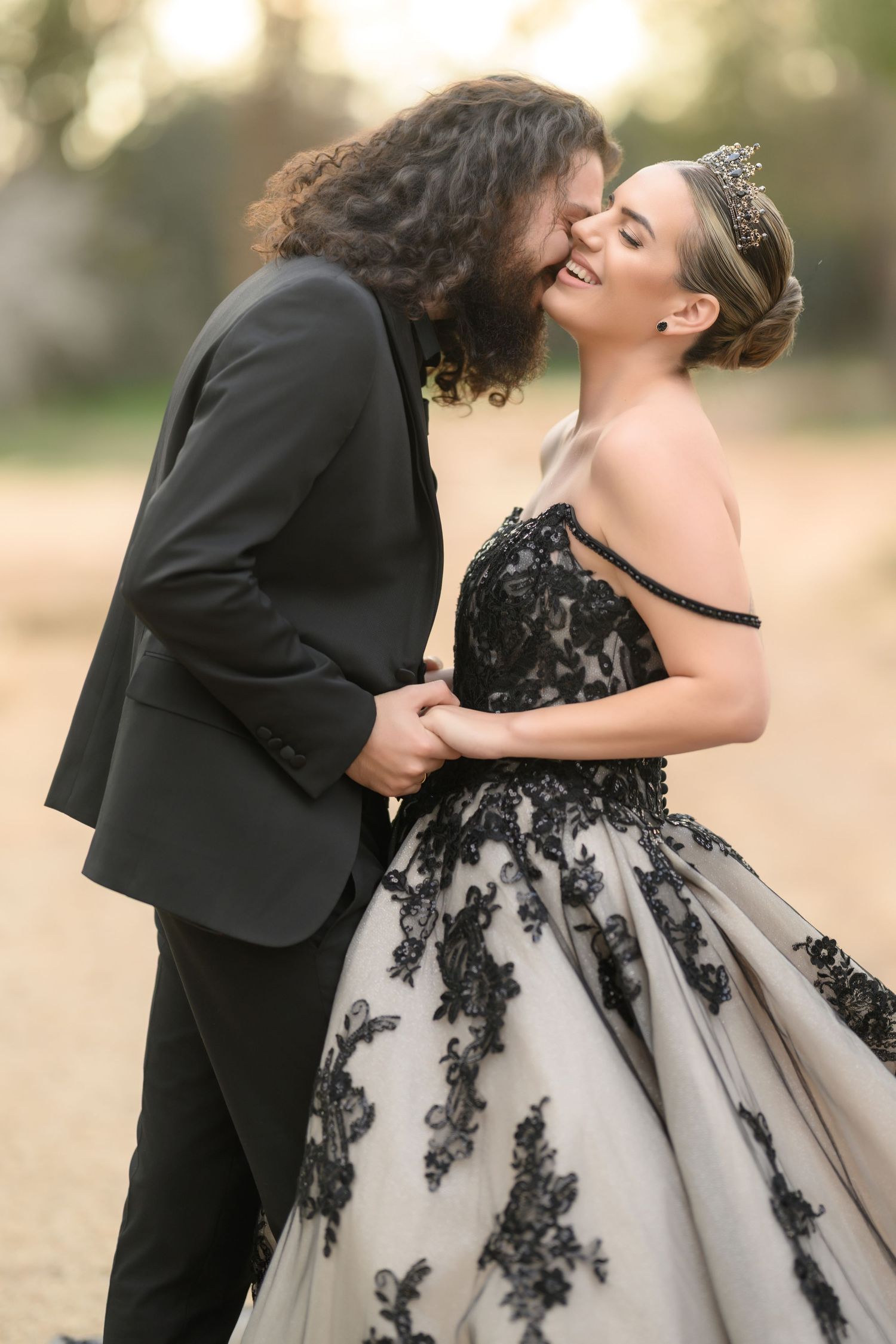 A couple shares a romantic moment in formal attire, with the bride wearing a stunning black and white lace ball gown.