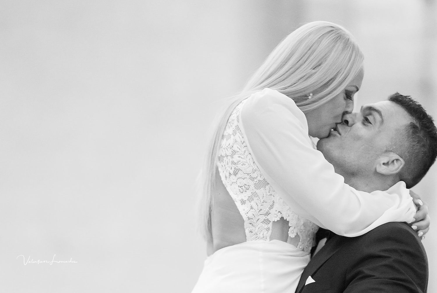 Black and white photograph capturing romantic wedding kiss.