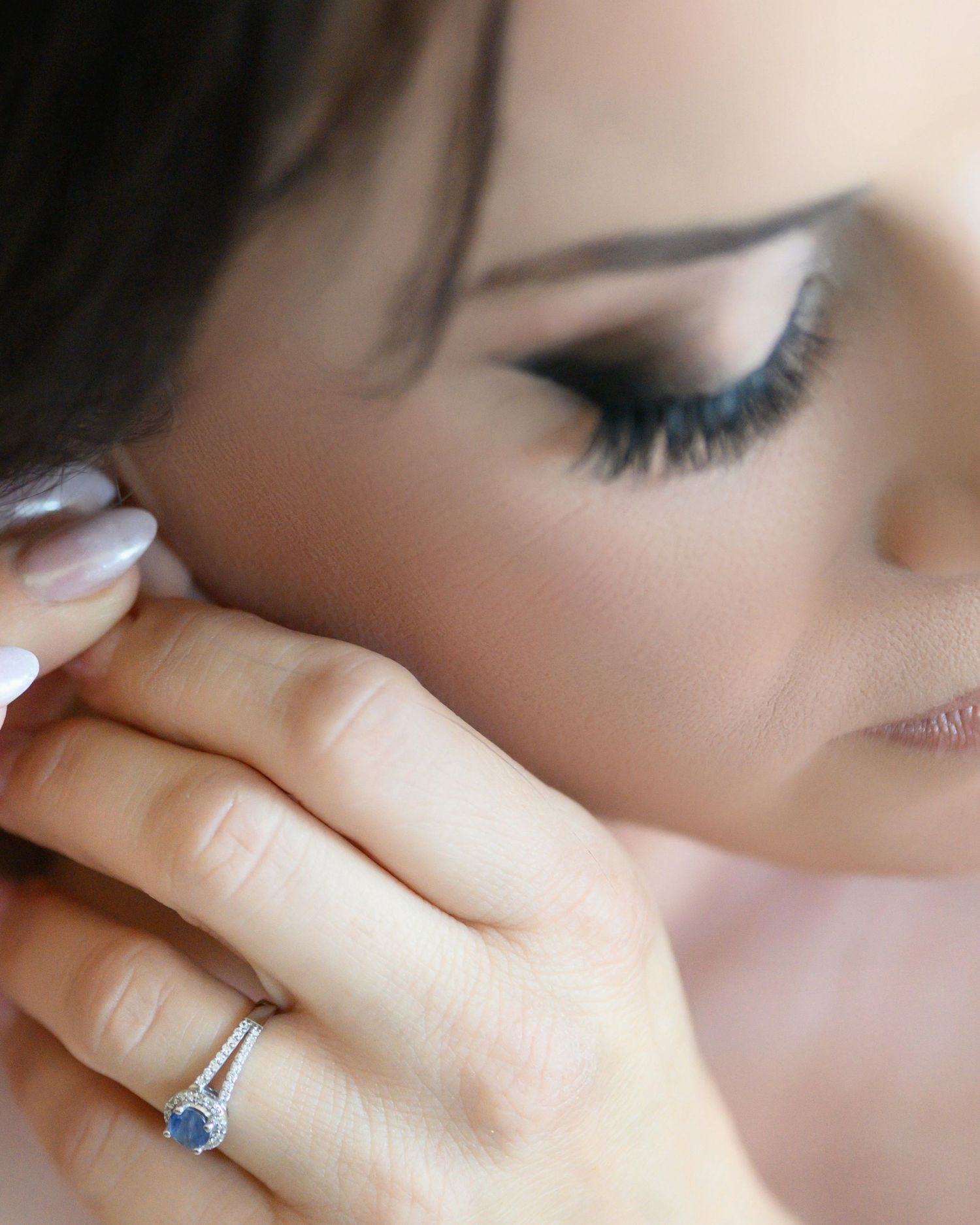 A sparkling sapphire engagement ring is showcased in different angles against soft blurred skin tones.