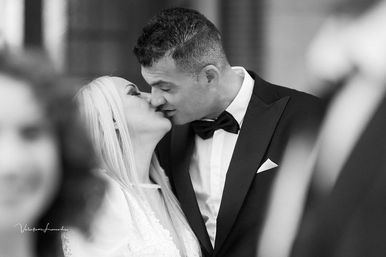 Black and white photograph of romantic wedding kiss moment.