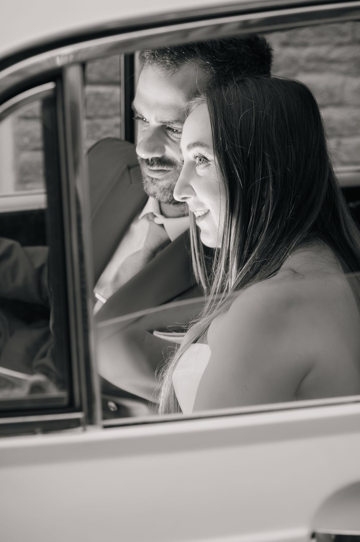 A couple shares a joyful moment inside a vintage car.