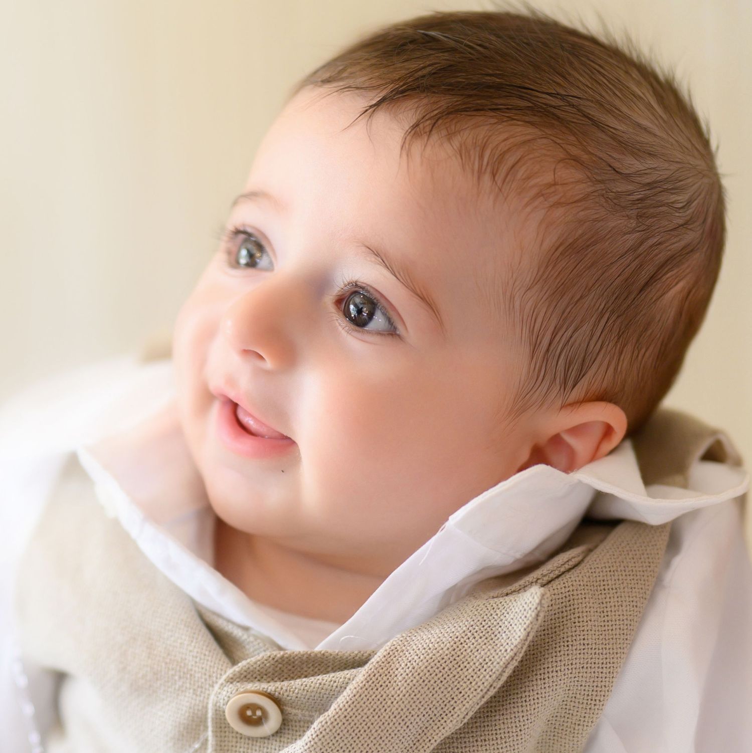 Close-up profile view of baby wearing neutral toned clothing in a soft natural light setting.
