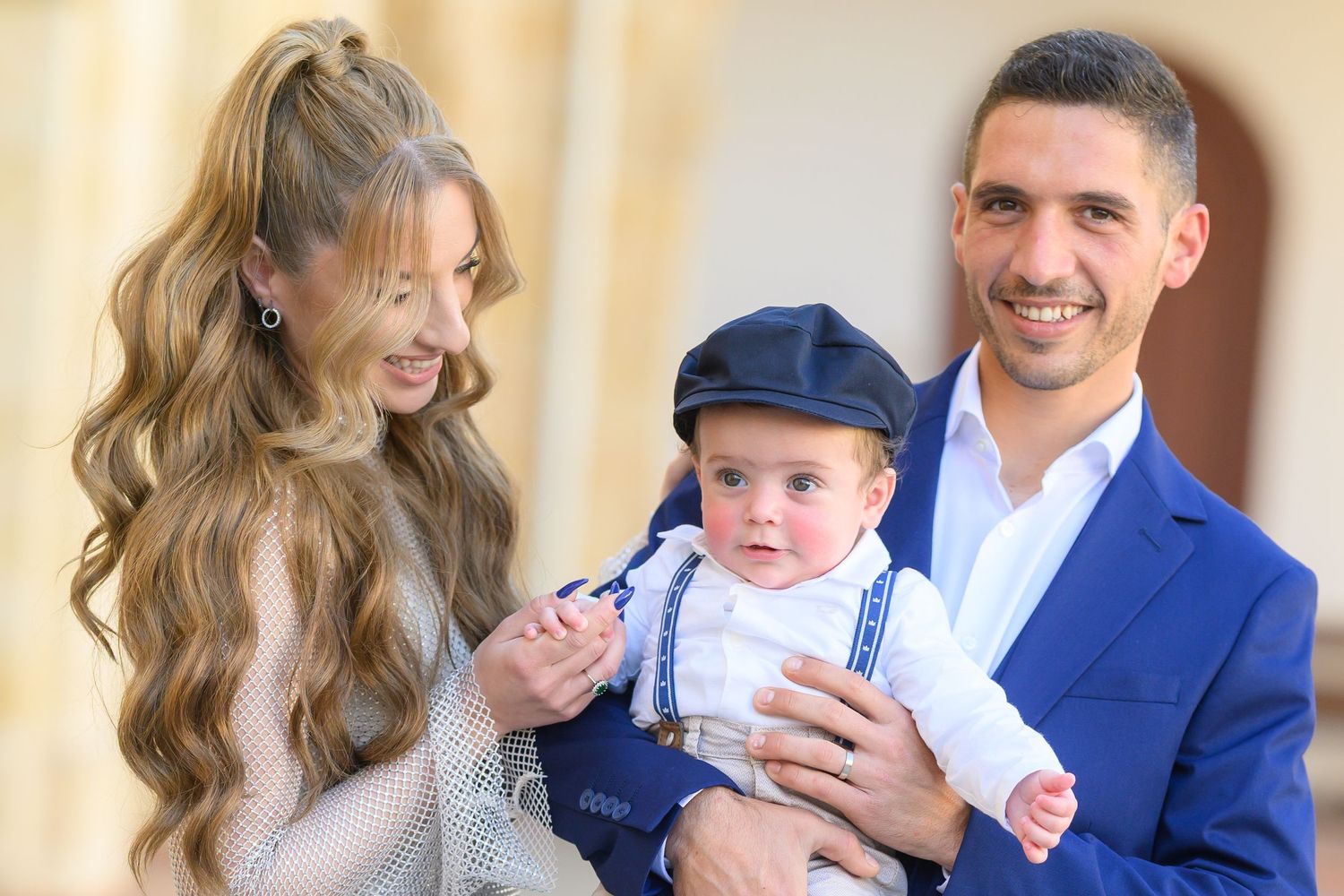 A series of photos showing joyful candid moments between parents and their baby in formal attire at an indoor venue.