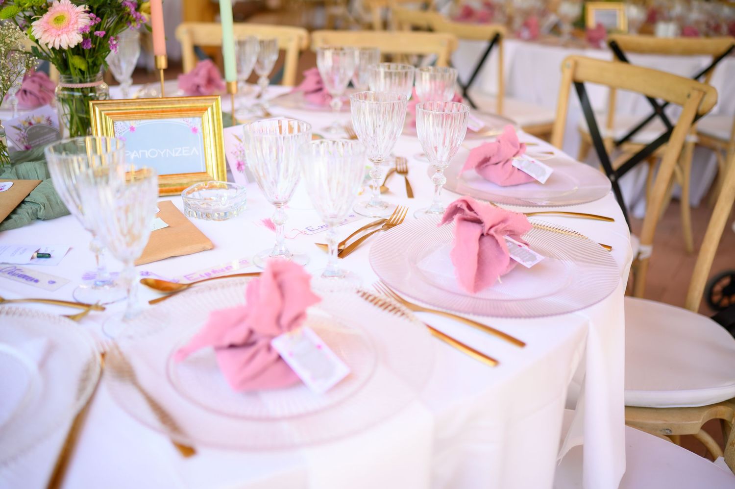 Elegant wedding table settings with pink floral decorations and white linens at an upscale reception venue.
