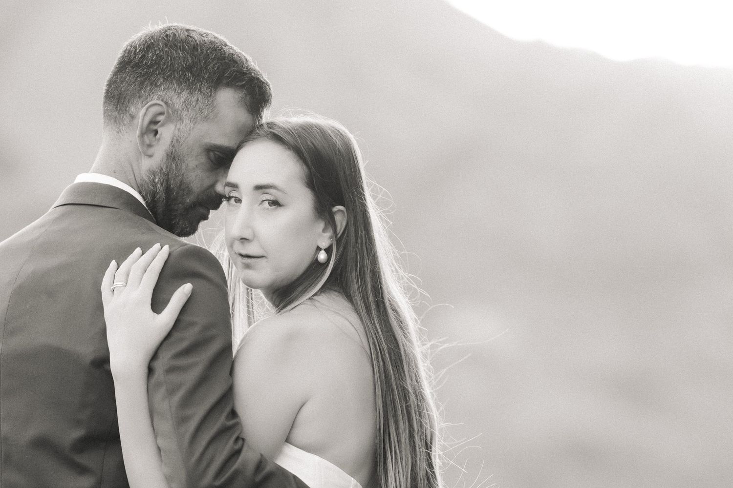 Artistic black and white wedding portrait against mountain backdrop.