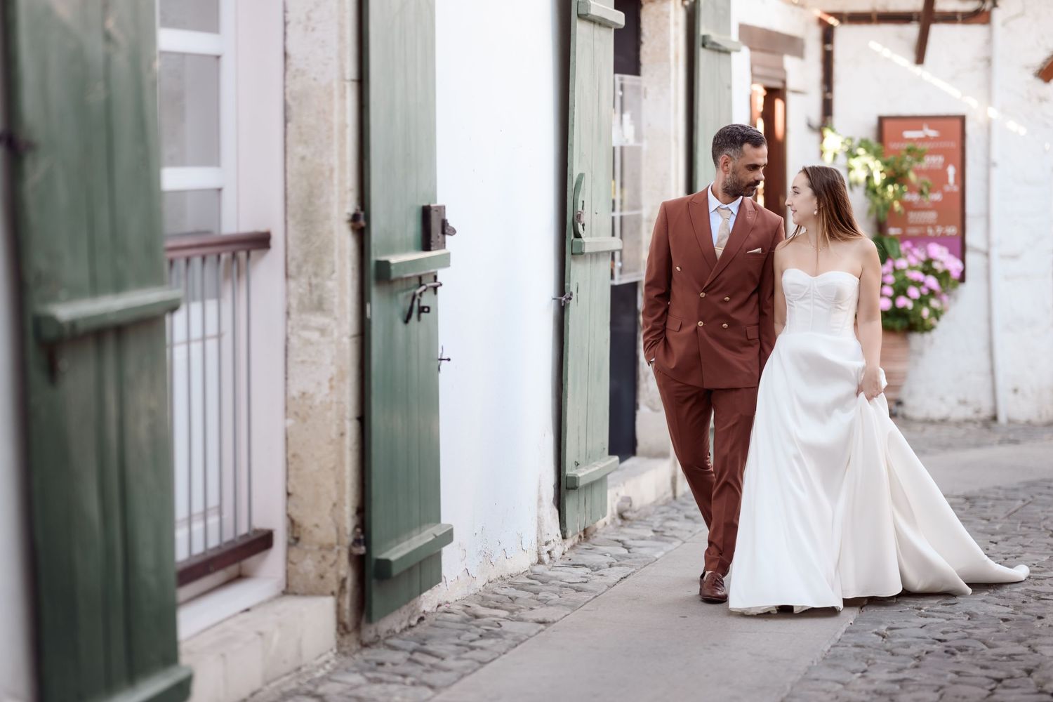 Wedding couple walking hand in hand down a charming European street.