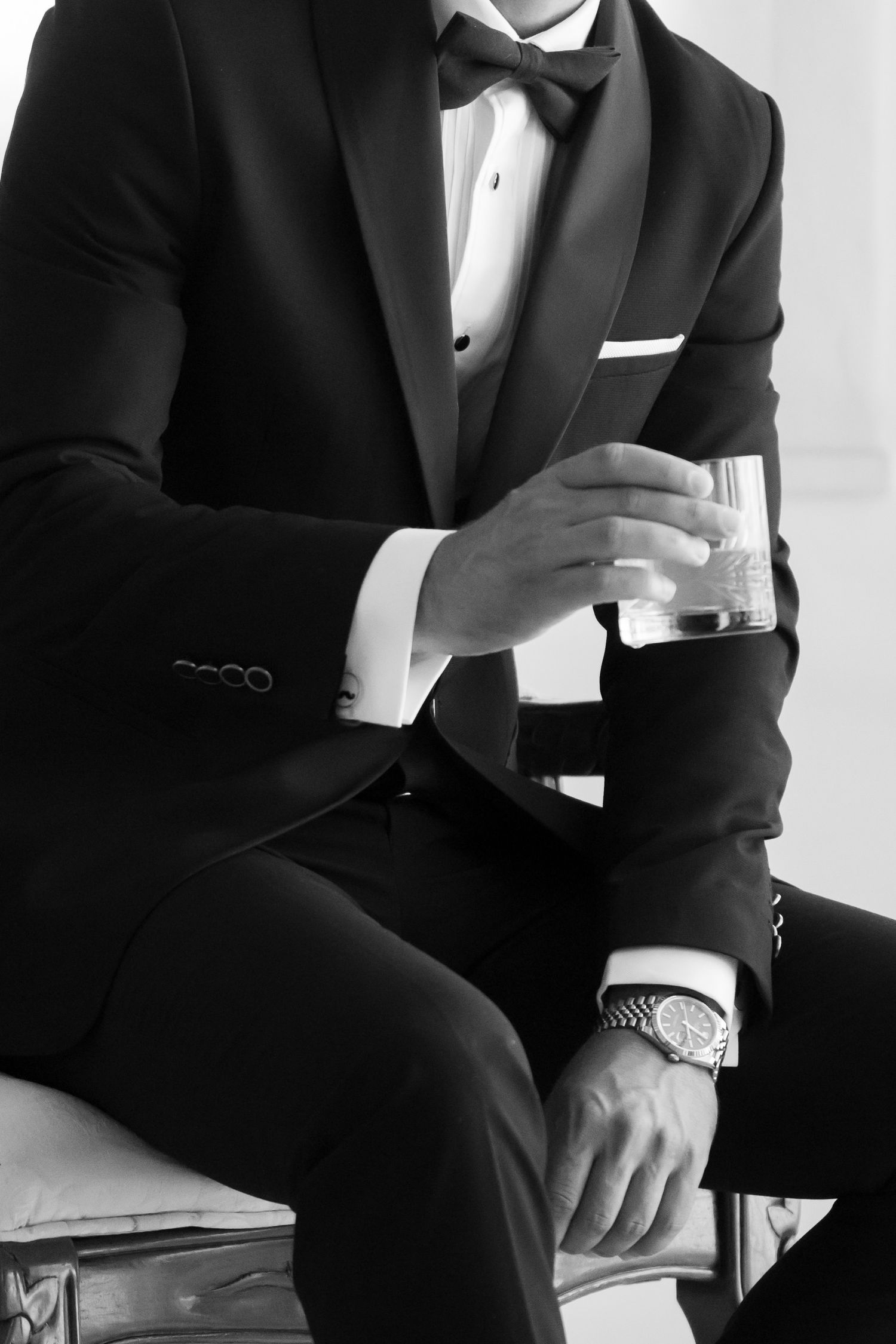 Black and white photo series showing details of a man in formal tuxedo attire sitting posed on dark furniture.