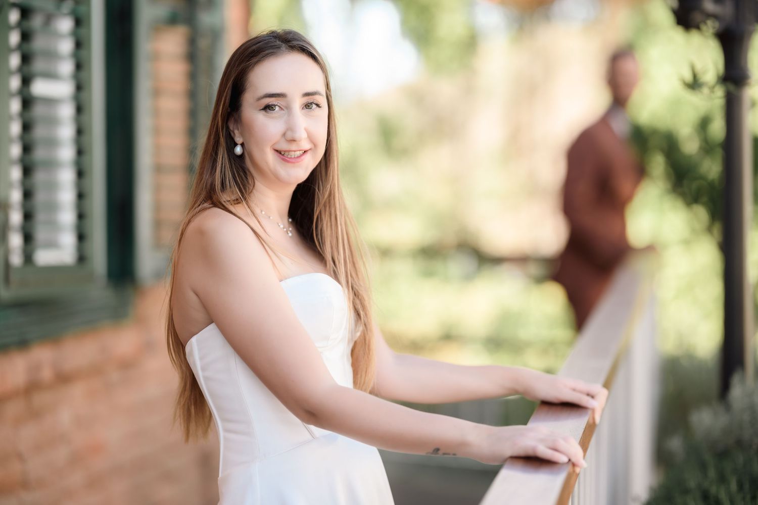 Bride in strapless white gown posing on rustic wooden deck.
