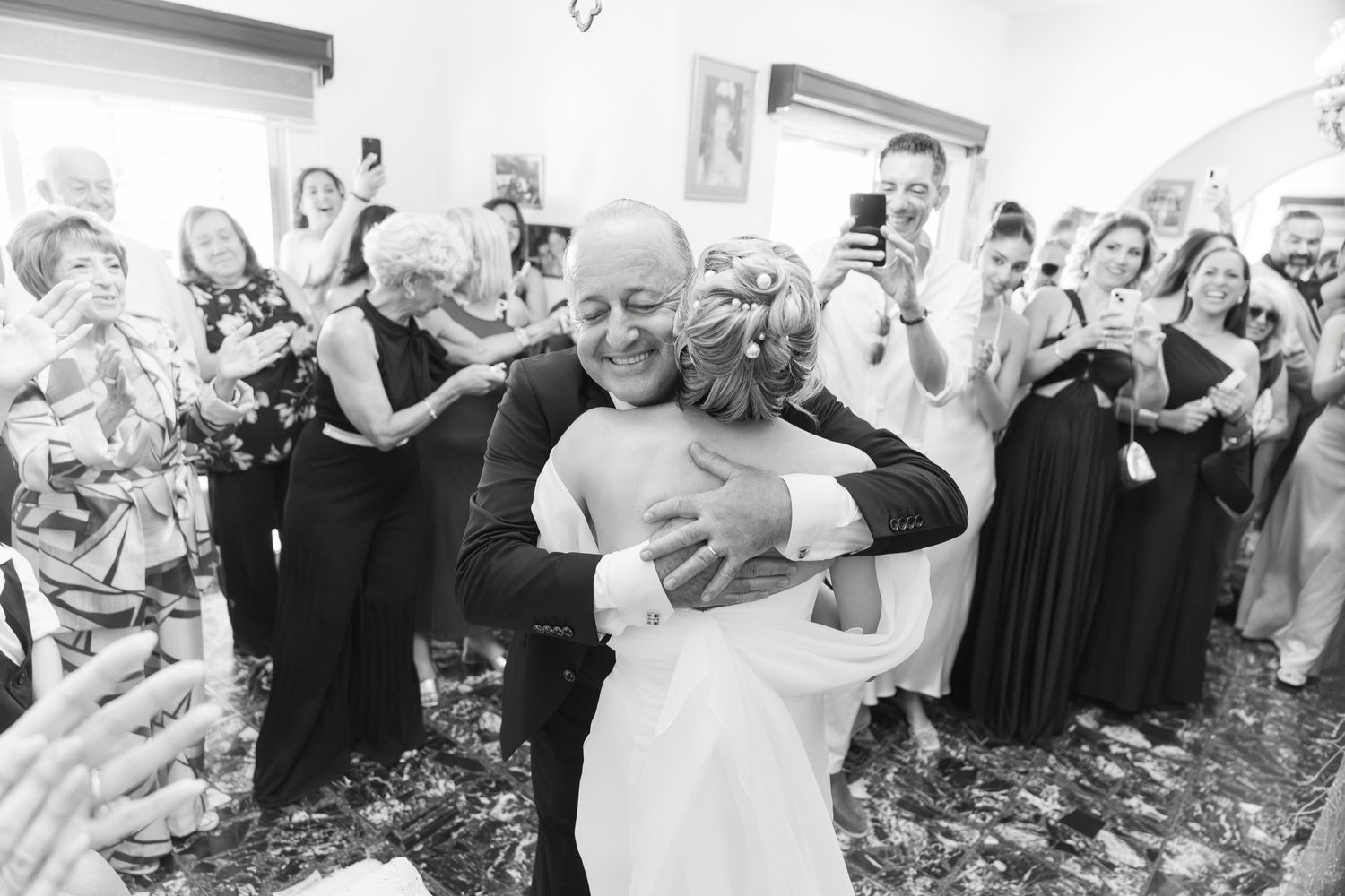Black and white photo of guests dancing and celebrating at a wedding party with confetti flying through the air.