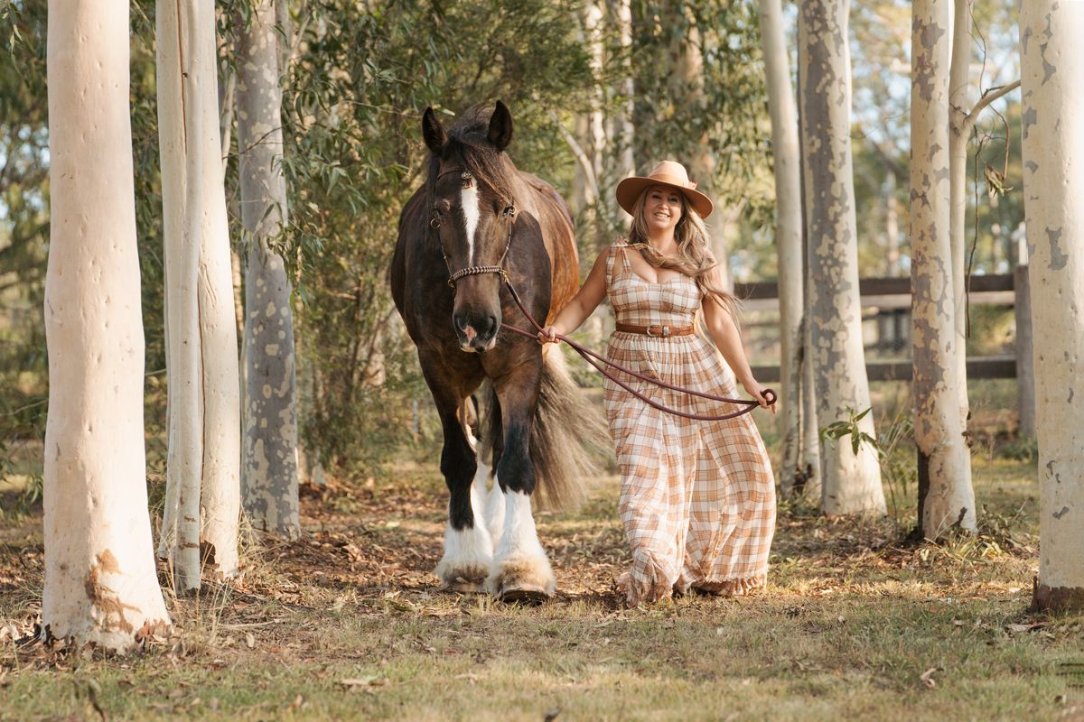 a girl poses with a horse in a scenic tree-lined path during an outdoor photoshoot with a horse in sydney