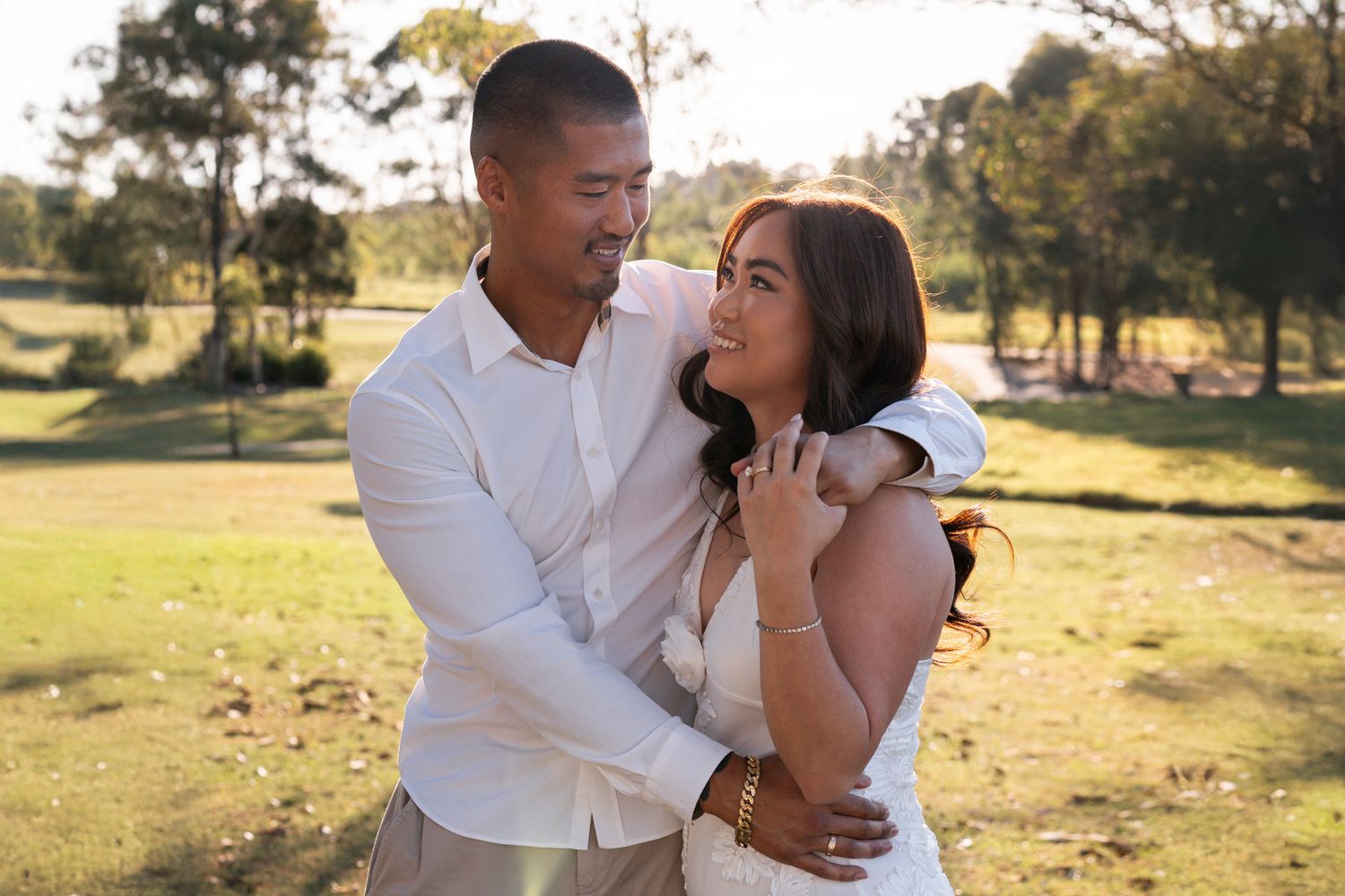 A romantic couple embraces in a sunny park setting during a golden hour elopement photoshoot in western sydney parklands