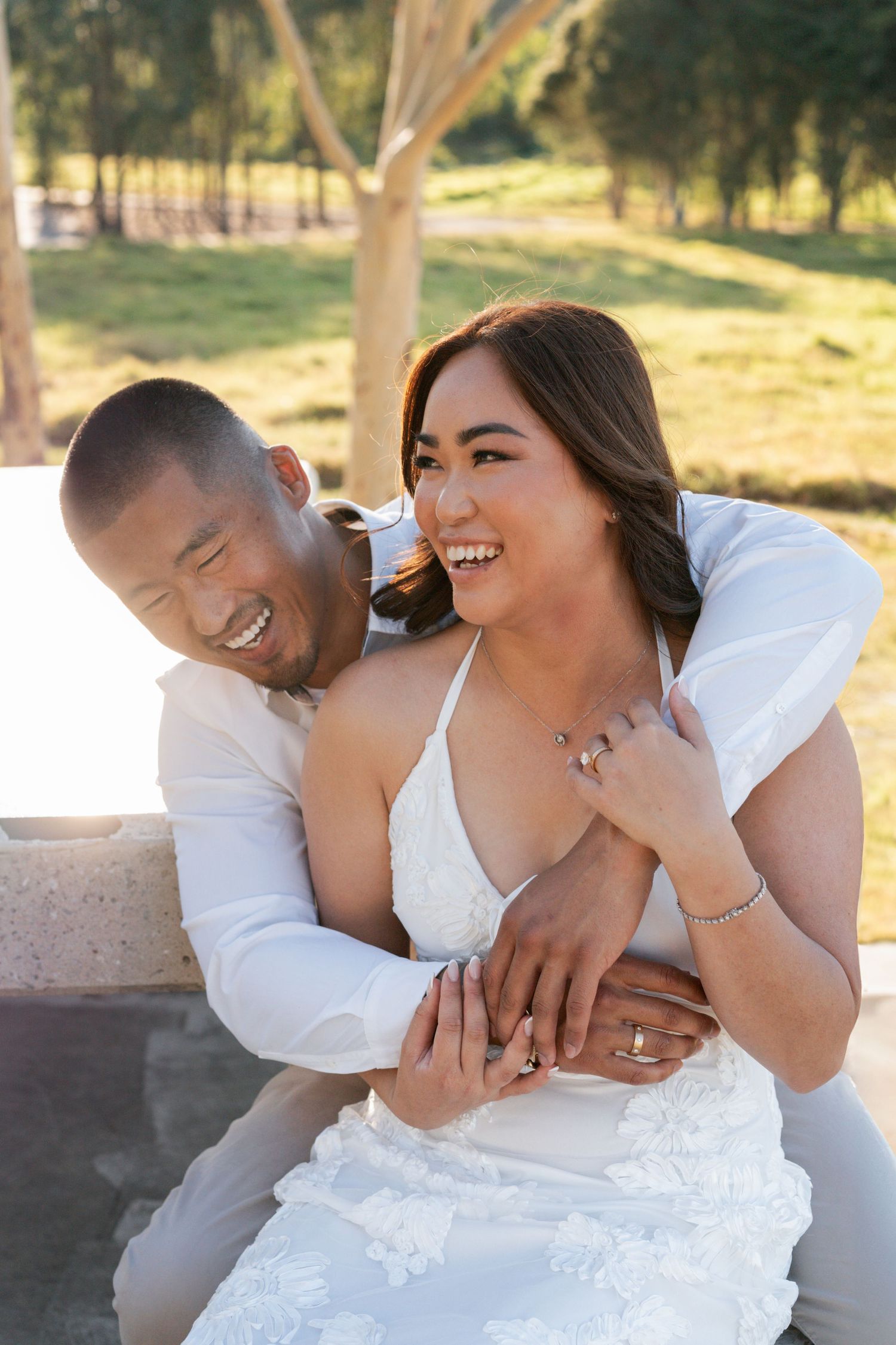 Happy couple sitting on the bench and laughing during a Valentines day photoshoot in the Western Sydney Parklands