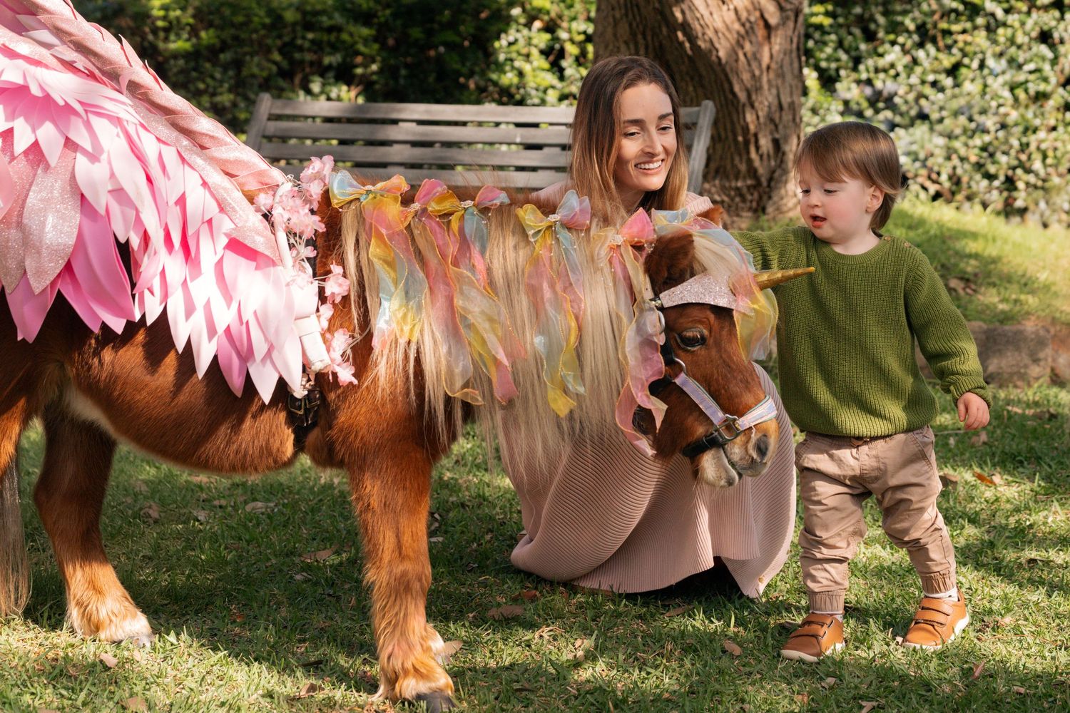 Mom and son petting a unicorn pony in a sunny garden setting during a family photshoot with a pony in Sydney