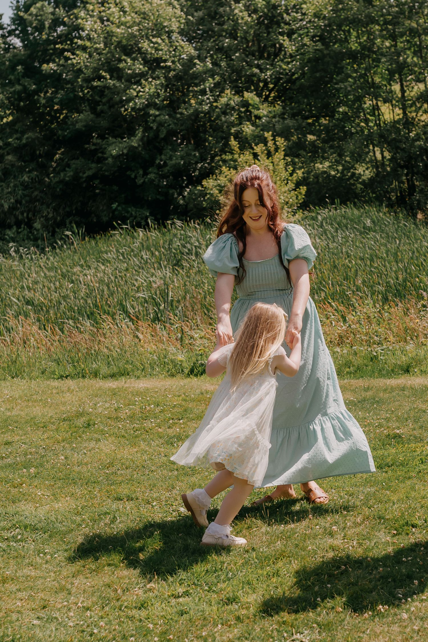mother spinning daughter around during a candid mother daughter family photoshoot.