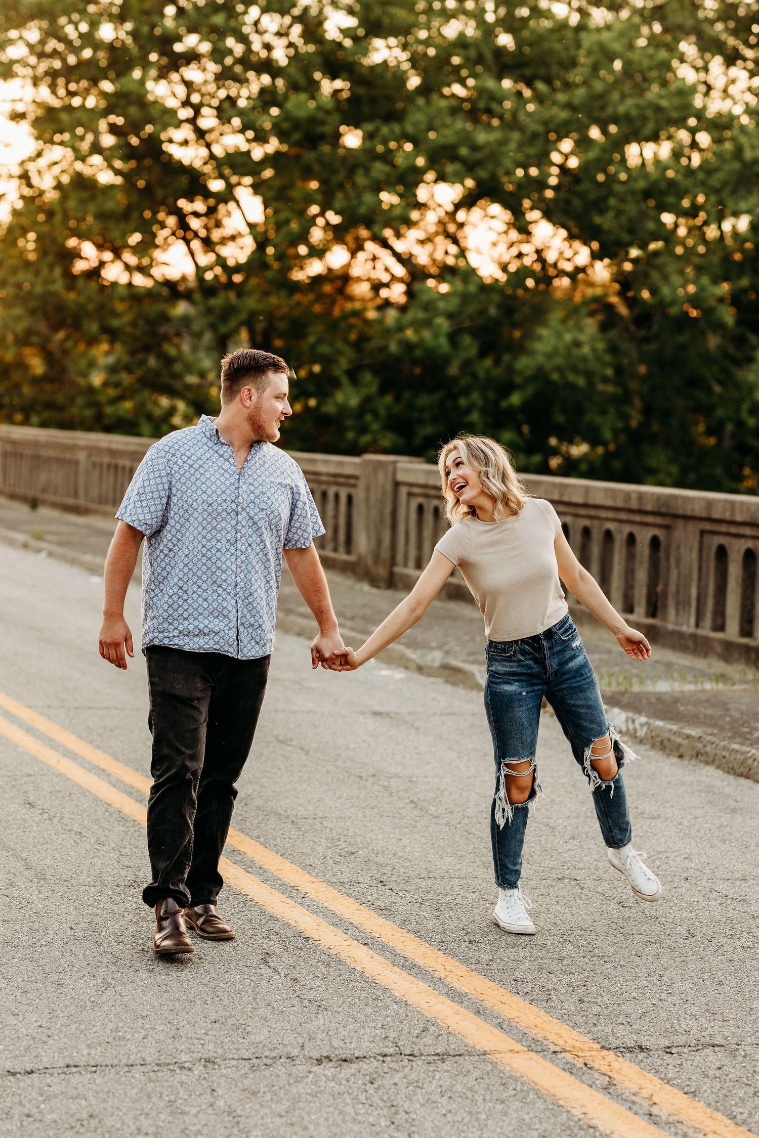 Couple holding hands while walking on a bridge during sunset.