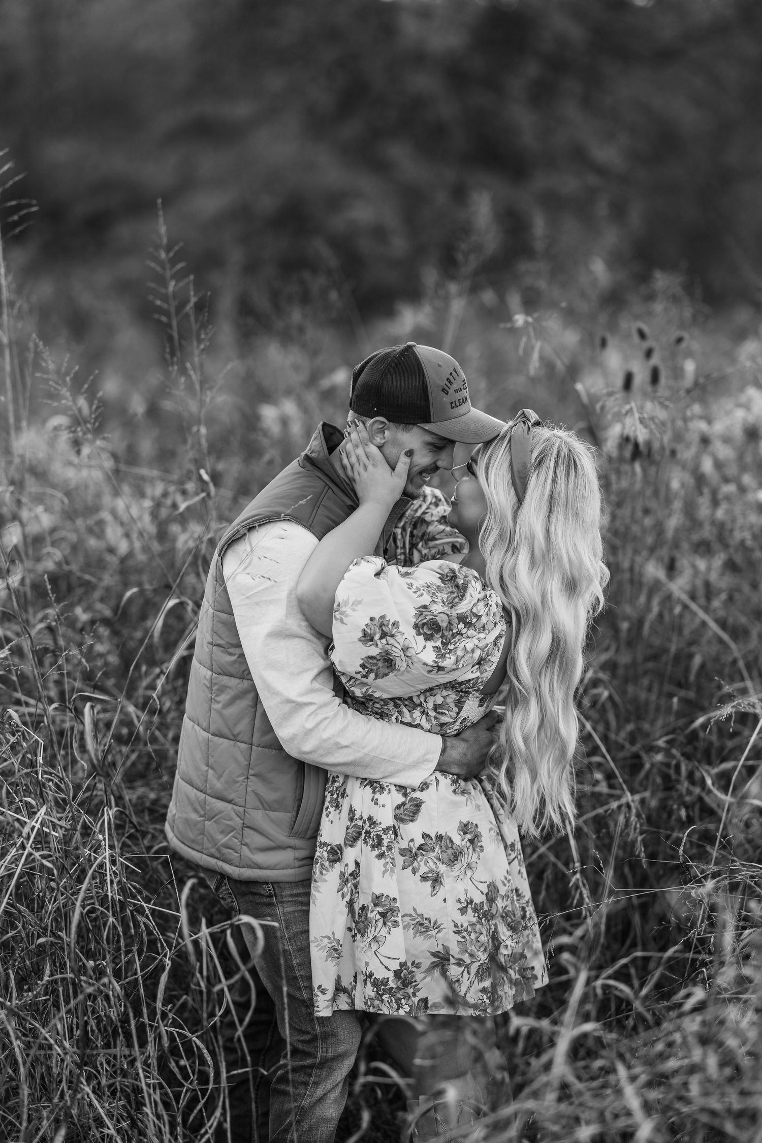 Couple embracing in tall grass field during black and white photoshoot.