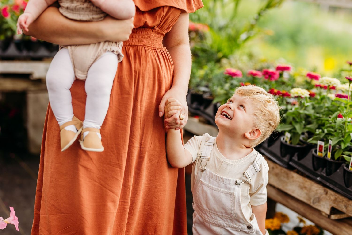 Candid family moment in garden with child laughing beside parent in orange dress.