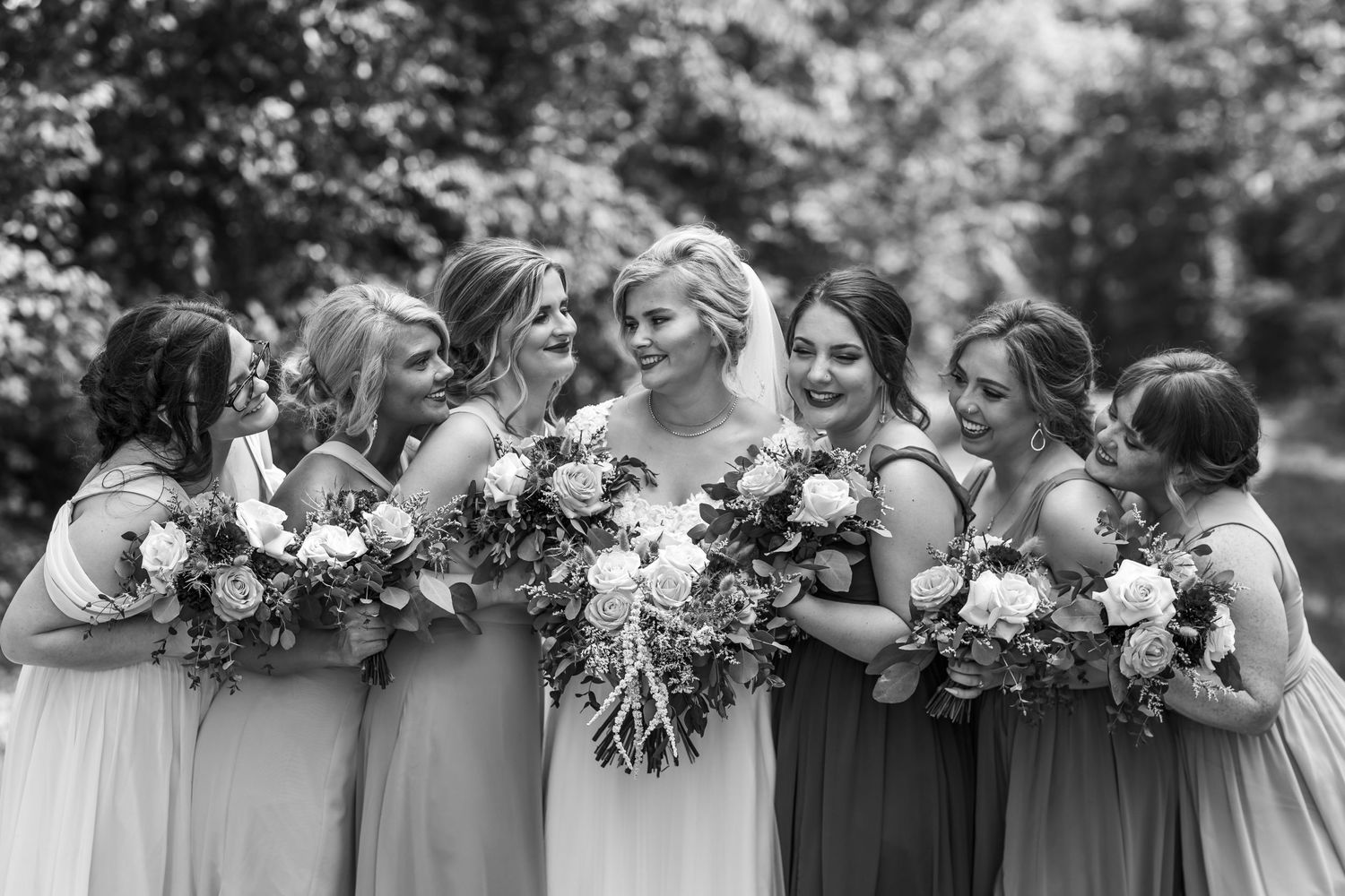 Intimate black and white portrait of bridal party sharing joyful moment with bouquets.