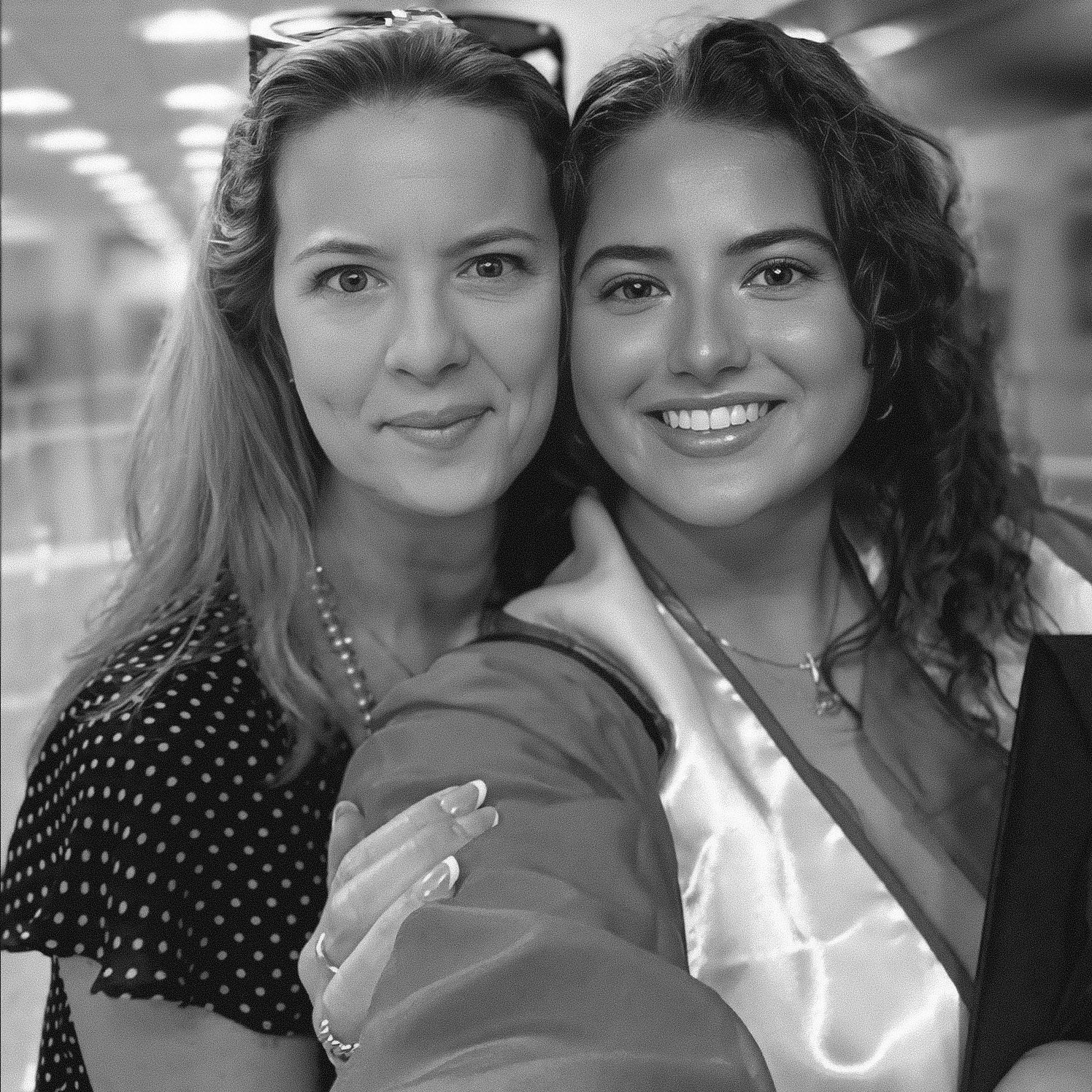 Two smiling women pose together for a selfie in a black and white photo indoors.