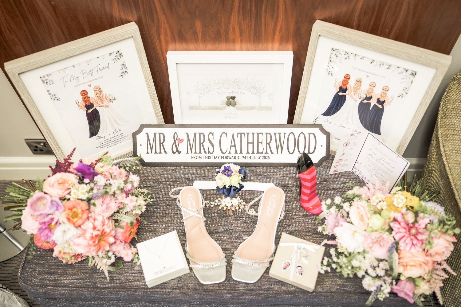 Wedding display table for Mr & Mrs Catherwood featuring bridal bouquets, framed portraits, heels, and decorative signs.