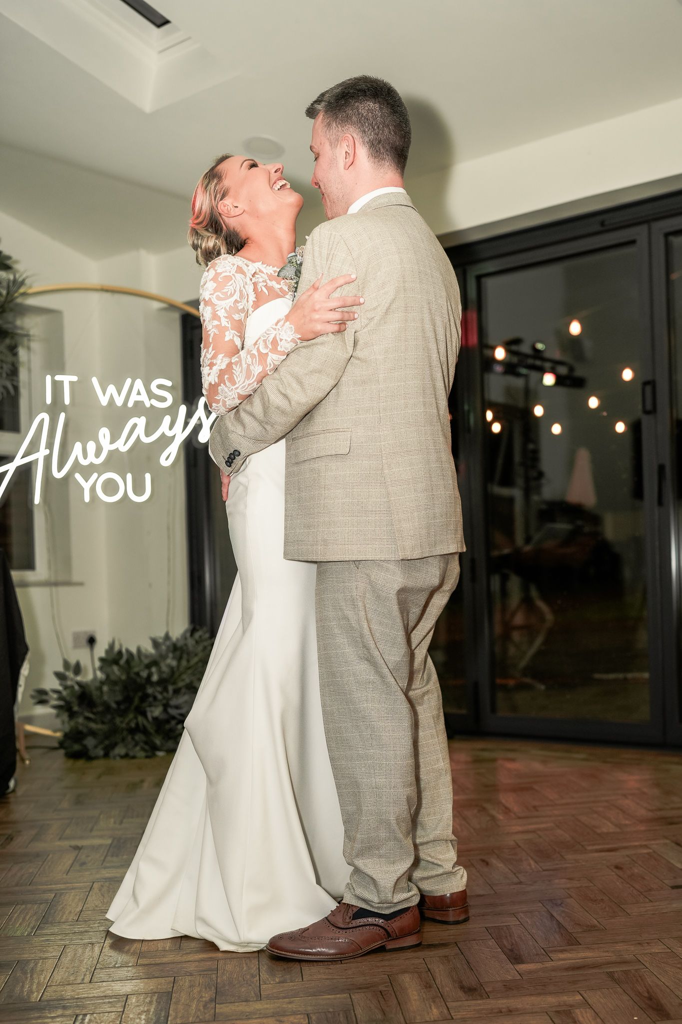 Bride and groom share first dance, embracing and laughing, with 