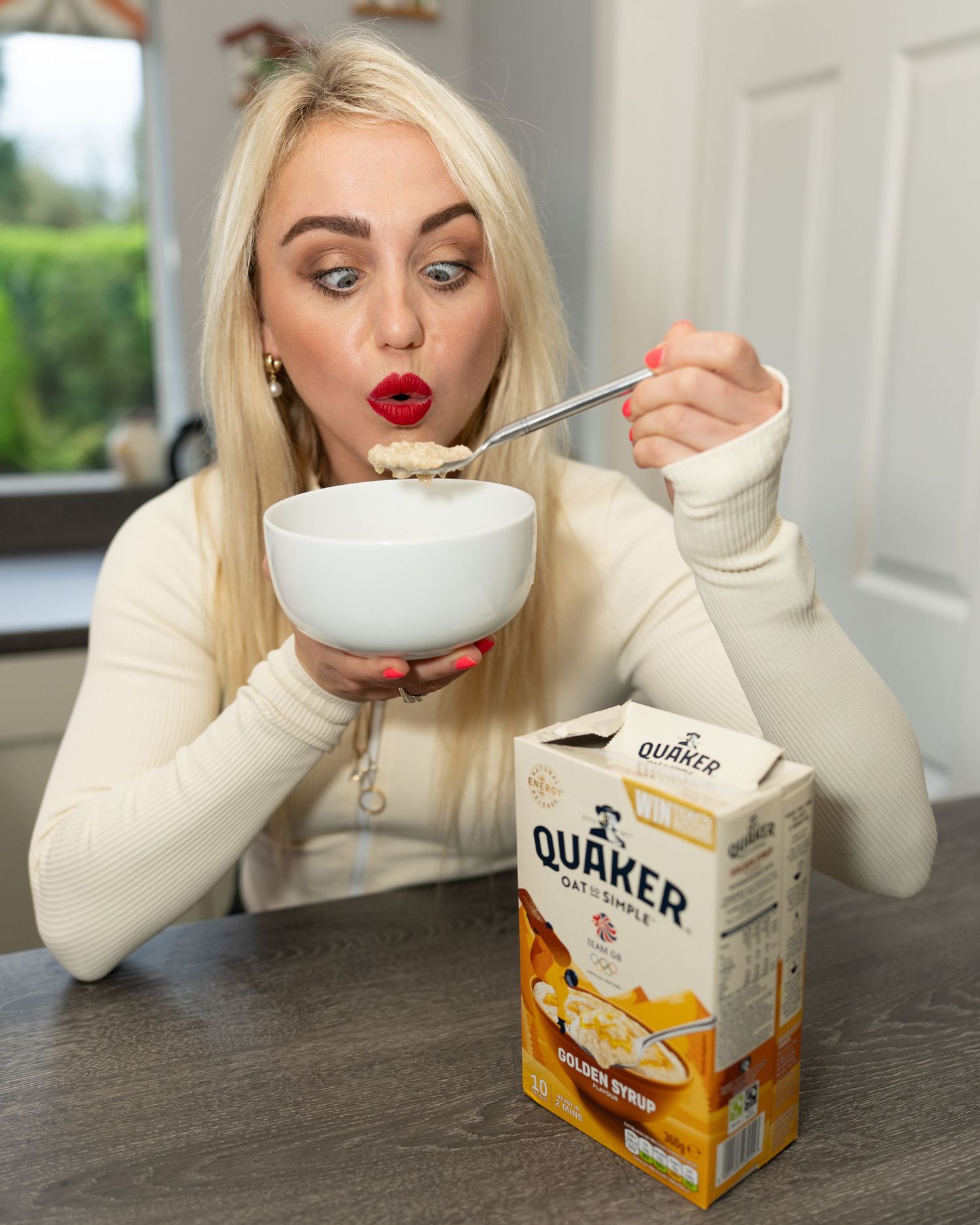 Blonde woman with red lips blowing on a spoonful of Quaker Golden Syrup oatmeal. Dave Martin Photography Studio Belfast