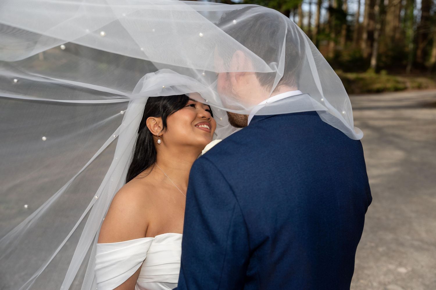 Bride and groom sharing an intimate moment under a flowing white wedding veil outdoors. Dave Martin Weddings Northern ireland