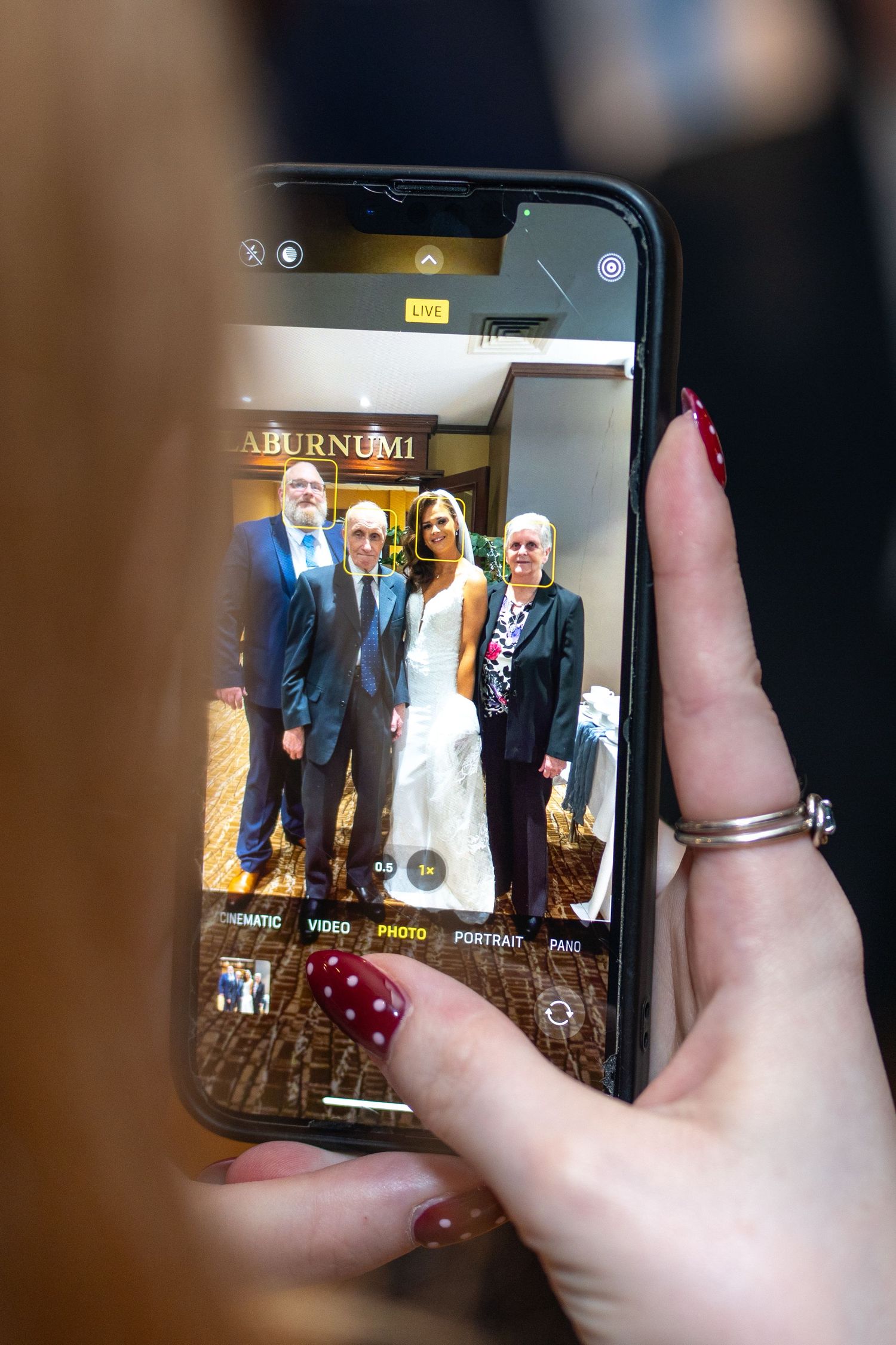 Phone screen showing bride posing with three guests at wedding reception venue. Dave Martin Photographer Northern Ireland