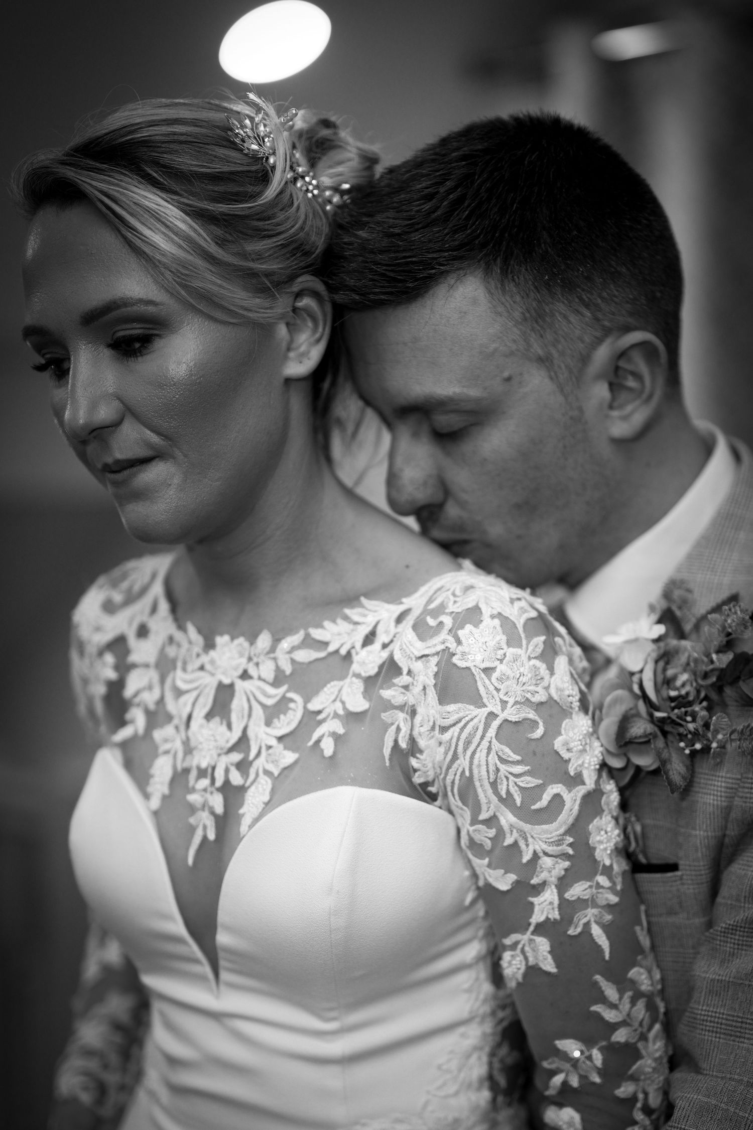 Black and white wedding photo of groom kissing bride on the neck. By Dave Martin