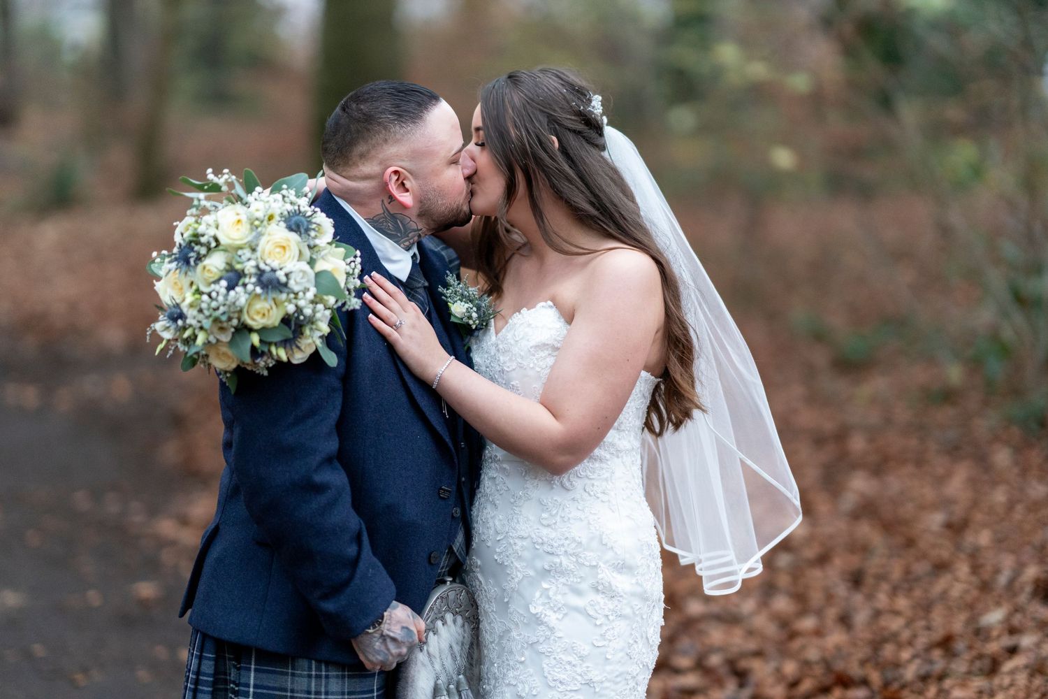 Bride and groom share romantic kiss in woodland setting with autumn foliage. Dave Martin Photographer Northern Ireland