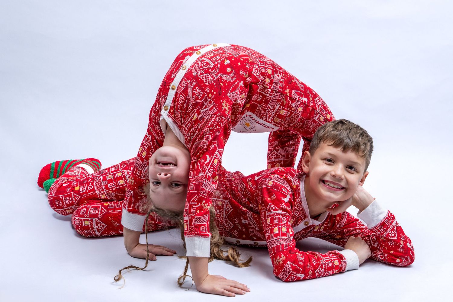 Two children in matching red Christmas pajamas playing on the floor. Dave Martin Photography Studio Belfast