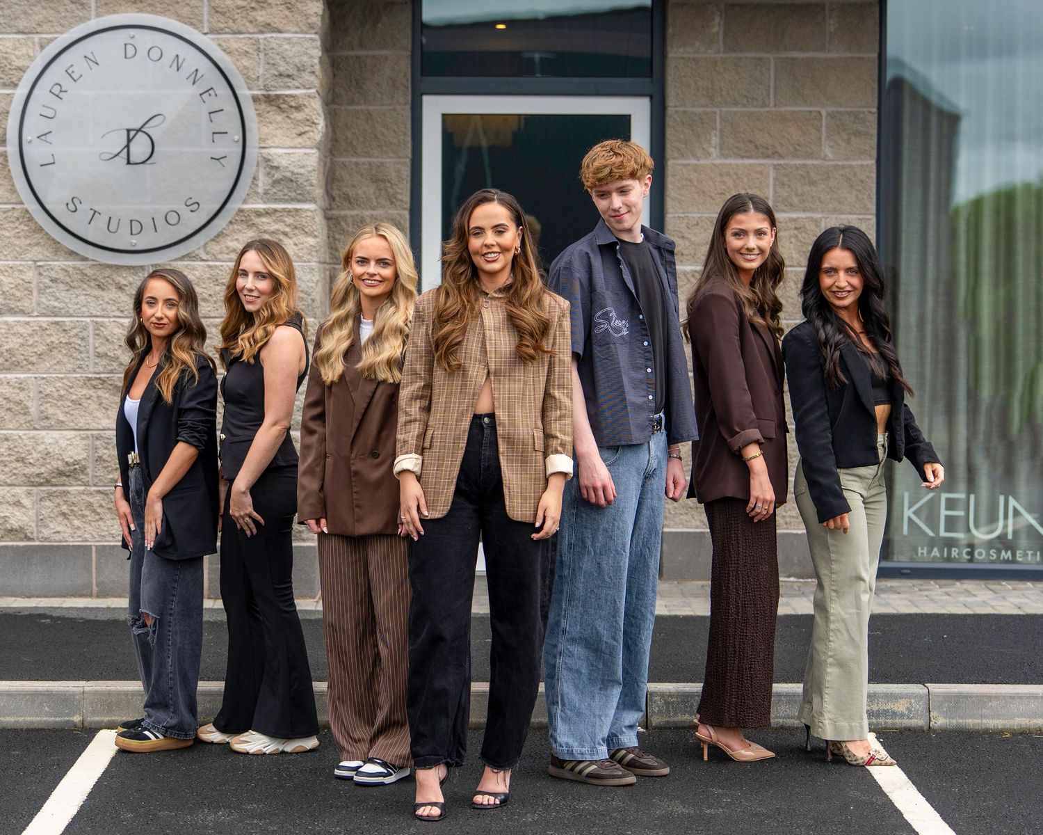 Group of seven young people posing outside Andres Donnelly Studios hair salon entrance. Dave Martin Photography Northern Ireland