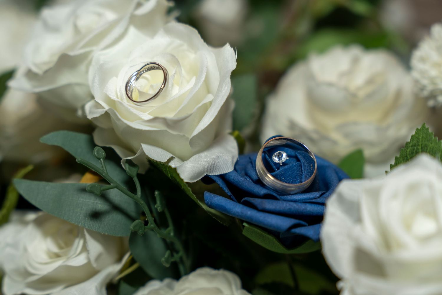 Wedding rings resting on white and blue roses in a bridal bouquet, symbolizing love and commitment. Dave martin Photo
